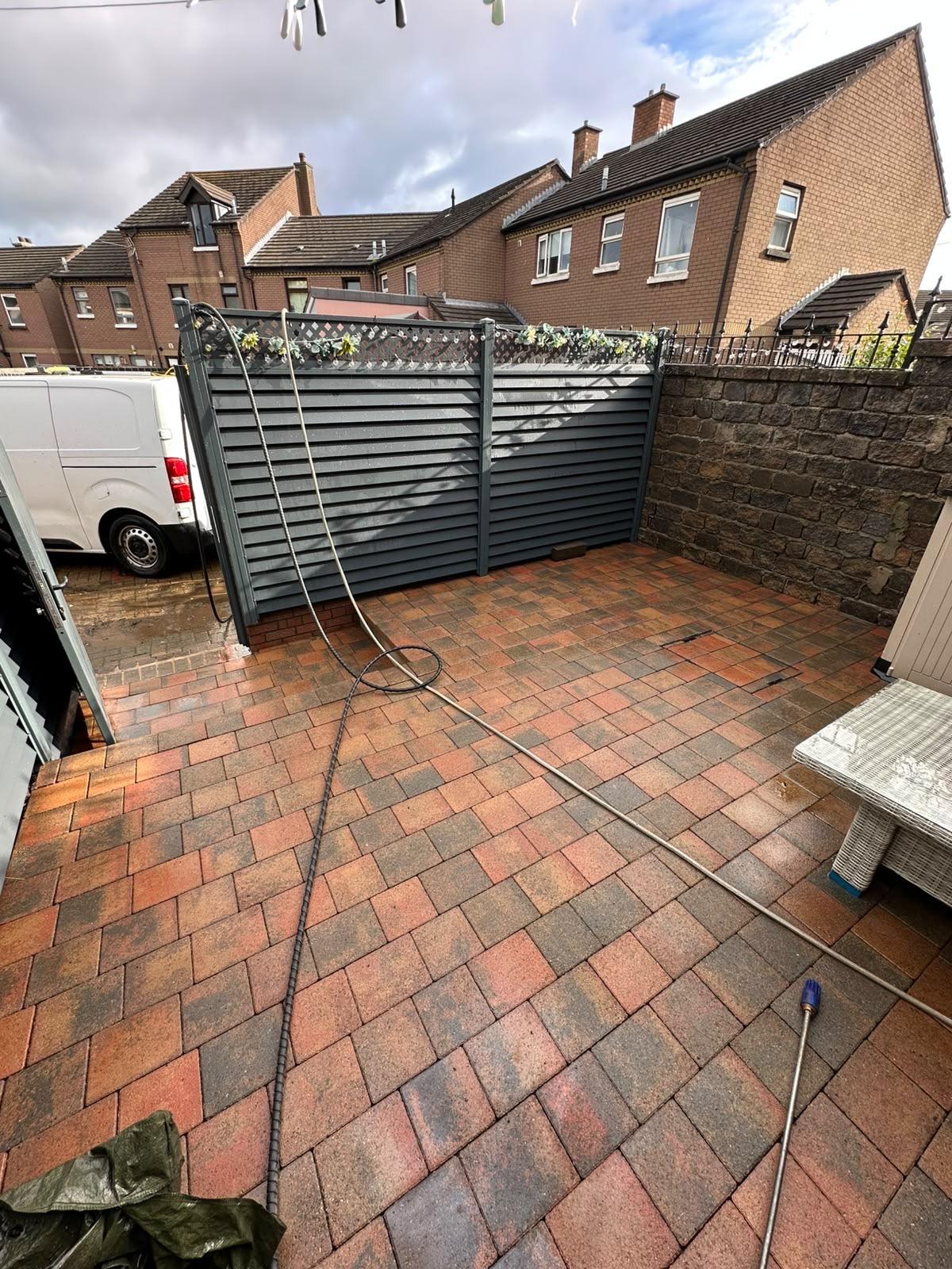 Back yard block paving with a pressure washer hose on the ground